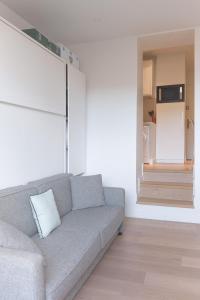 sala de estar con sofá gris y escalera en Un Écrin au Suquet - Studio, clim, balcon, plage, Palais des Festivals, en Cannes