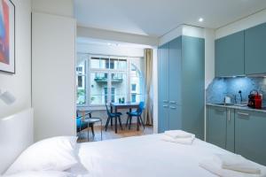 a bedroom with a white bed and a kitchen at HITrental Riesbach Apartments in Zurich