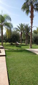 a park with palm trees and a bench in the grass at Villa Luxe in Marrakech