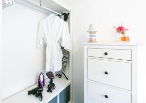 a closet with a white coat and shoes on a shelf at Central Gunwharf Quays Two Bedroom apartment in Portsmouth