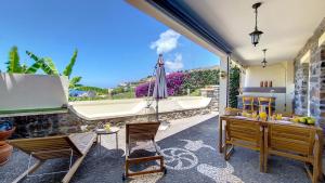 a patio with a tub and chairs and a table with an umbrella at Bohome Nest by LovelyStay in Arco da Calheta