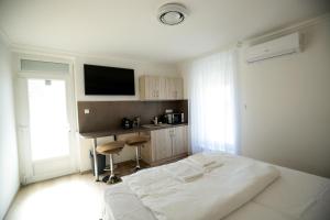 a white bedroom with a bed and a desk at Markó Vendégház in Kiskőrös