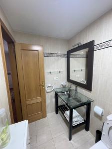 uma casa de banho com um lavatório de vidro e um espelho. em Apartamento acogedor próximo a playas y aeropuerto em La Coruña