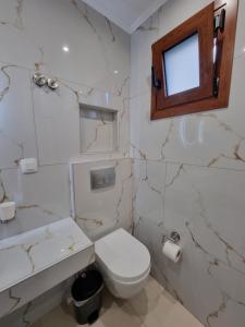 een badkamer met een toilet, een wastafel en een raam bij Bellos House in Parga