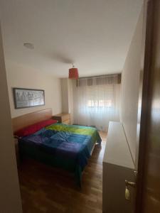 um quarto com uma cama com um edredão colorido em Apartamento acogedor próximo a playas y aeropuerto em La Coruña