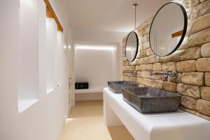 a bathroom with two sinks and a stone wall at Utopia Suites by Anna Platanou in Agia Irini Paros