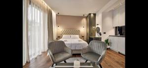 a bedroom with a bed and two chairs and a table at Amuse Luxury Apartments in Zakynthos