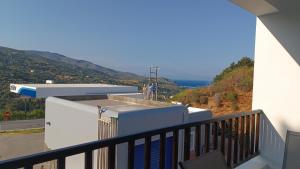 un balcón con vistas al océano en una colina en Azalea Guesthouse, en Ándros