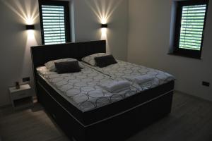 duże łóżko w sypialni z dwoma oknami w obiekcie House Under The Maple Tree w mieście Vitanje