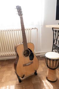 a guitar sitting next to a stool in a room at Passero Holiday House in Moravske-Toplice