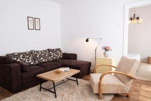 a living room with a brown couch and a chair at Passero Holiday House in Moravske-Toplice