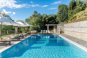 a swimming pool with benches and umbrellas next to a brick wall at Bellosta Family Country Club MB Alpe Moiana in Armeno
