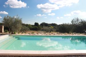 a swimming pool with chairs and a blue sky at Gîte La Grange de Cournon in Argelliers