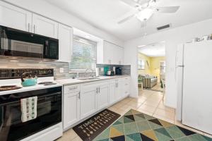 La cuisine est équipée de placards blancs et d'un réfrigérateur blanc. dans l'établissement Beach Villa A, à Clearwater Beach