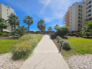 a walkway through a park with palm trees and buildings at River Terrace & Pool View - Seixal in Seixal