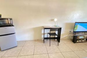 a room with a desk with a microwave and a television at Blissful Studio in Hallandale Beach 8mins to beach in Hallandale Beach