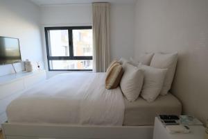 a white bed with white pillows and a window at River Terrace & Pool View - Seixal in Seixal +45 photos