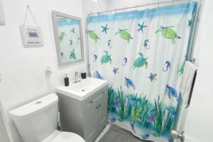 La salle de bains est pourvue d'un rideau de douche avec des poissons. dans l'établissement Peaceful Beachy Oasis 10 Mins from Beaches, à North Miami Beach