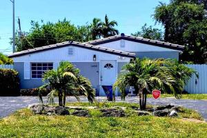 un bâtiment blanc avec des palmiers devant lui dans l'établissement Peaceful Beachy Oasis 10 Mins from Beaches, à North Miami Beach