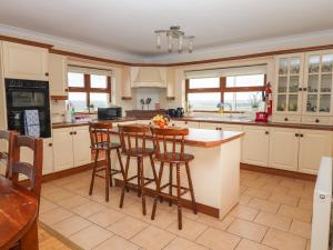 a kitchen with white cabinets and a island with bar stools at Lackamore in Lahinch