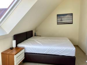a bedroom with a white bed and a wooden table at Ferienhaus Grodenblick Strandflieder Whg. 2 in Wangerooge