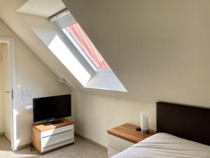 a bedroom with a skylight and a bed and a television at Ferienhaus Grodenblick Strandflieder Whg. 2 in Wangerooge