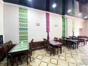 a restaurant with tables and chairs in a room at Polvon Ota Hotel in Khiva