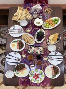 a table with plates of food on top of it at Polvon Ota Hotel in Khiva