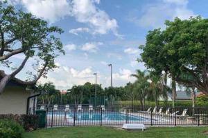 a swimming pool with chairs behind a fence at Tropical Oasis home w Community Pool great area in Kendall