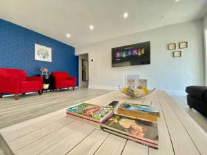 a living room with a table with books and red chairs at Royal Luxe Pool Home near Ft Laud airport and each in Lauderhill