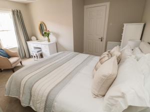 a bedroom with a white bed with a chair and a desk at Charter's Cottage in Berwick-Upon-Tweed