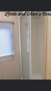 een badkamer met een douche en een raam en een douche bij Linda/Alan's Happy Holiday Home in Rhyl