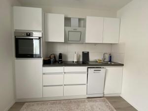 a white kitchen with white cabinets and appliances at Dream Apartments in Hohenems