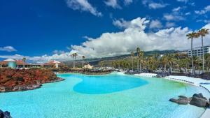 a pool at a resort with blue water and palm trees at Villa la Paz in Puerto de la Cruz