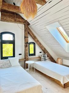 two beds in a room with wooden ceilings and windows at Ublik Stacja in Ublik