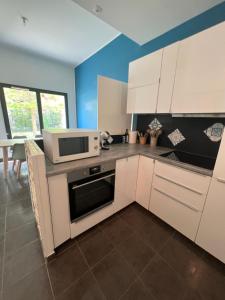 a kitchen with white cabinets and a microwave at Charment Appartement T3 Palaiseau Camille Claudel in Palaiseau