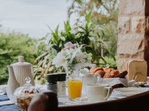 - une table avec des aliments pour le petit-déjeuner, du jus d'orange et des fleurs dans l'établissement Ridgeview Lodge, à Durban