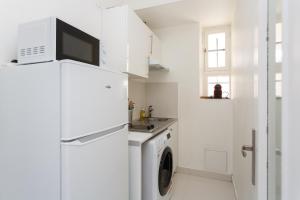 a white kitchen with a refrigerator and a washing machine at LE BOURGET RER F2 2ème gauche in Le Bourget