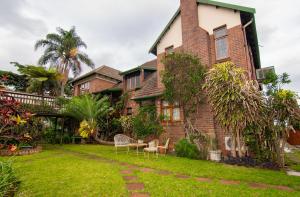 une grande maison en briques dotée d'une cour avec des chaises dans l'établissement Ridgeview Lodge, à Durban