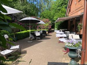 a patio with tables and chairs and an umbrella at Tangstedter Mühle in Tangstedt