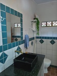 ein Bad mit einem schwarzen Waschbecken und blauen und weißen Fliesen in der Unterkunft Chalé Aconchego 