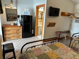 Buffalo Chip's Ranch House Motel في بونيتا سبرينغز: غرفة معيشة فيها سرير وثلاجة سوداء