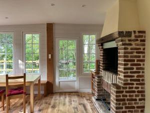 a living room with a brick fireplace and a dining table at La Maison de l'Etang in Manerbe