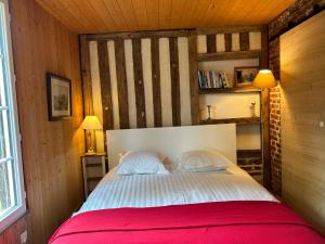 a bedroom with a white bed with a red blanket at La Maison de l'Etang in Manerbe