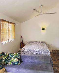 a bedroom with a bed with a ceiling fan and a couch at El Patio Cultural in Las Terrenas