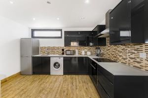 a kitchen with black cabinets and a washer and dryer at Marylebone City Apartments in London