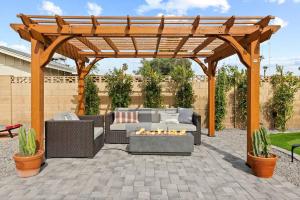 a wooden pergola with a couch and a fire pit at El Descanso in Meyer Park - Heated Pool in Tempe
