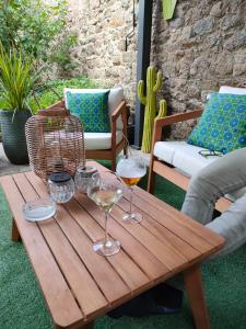 einen Holztisch mit zwei Gläsern Wein auf einer Terrasse in der Unterkunft La suite 27, chambre d'hôtes de charme in Guingamp