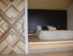 1 dormitorio con una pared de madera y 1 cama en Unic loft Sapa - Massif Charlevoix, Mont-St-Anne, en Saint-Joachim