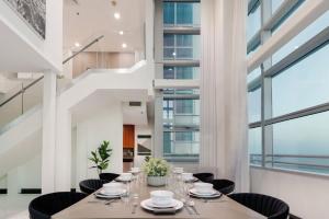 een eetkamer met een tafel en stoelen en grote ramen bij Roami at Brickell Penthouse Squad Oasis in Miami